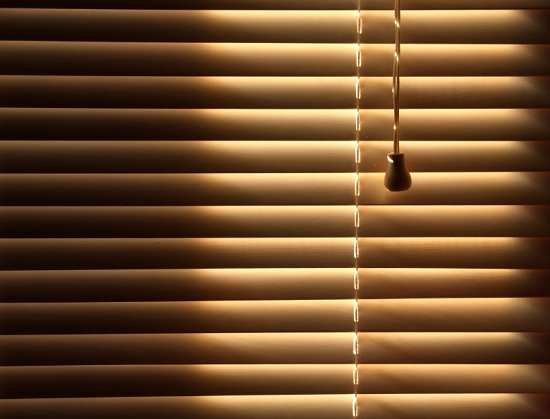 Sun blocked by wooden venetian blinds